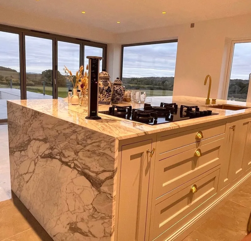A kitchen island with a heavily veined worktop and matching sides, in a countryside home
